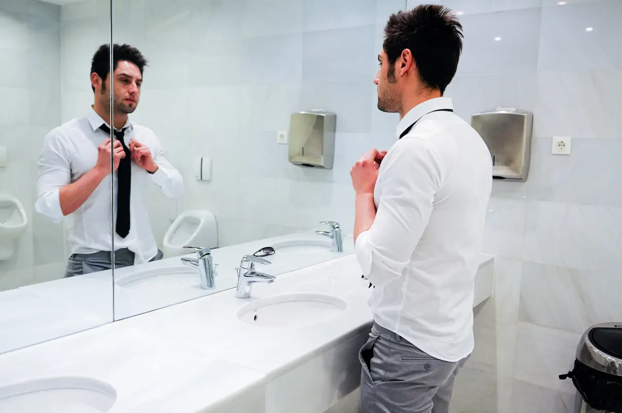 Hombre atractivo mirándose al espejo mientras deja su "memoria" en el agua que toca su cuerpo